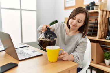 Down sendromlu esmer kadın iş yerinde bir fincan kahve içiyor.