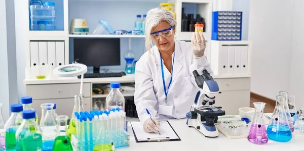 科学者の制服を着た中年女性研究室で尿分析検査管を保持 — ストック写真