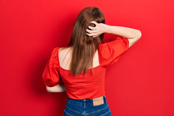 Kızıl Saçlı Kırmızı Tişörtlü Genç Bir Kadın Tersten Kuşkulandığını Düşünüyor — Stok fotoğraf