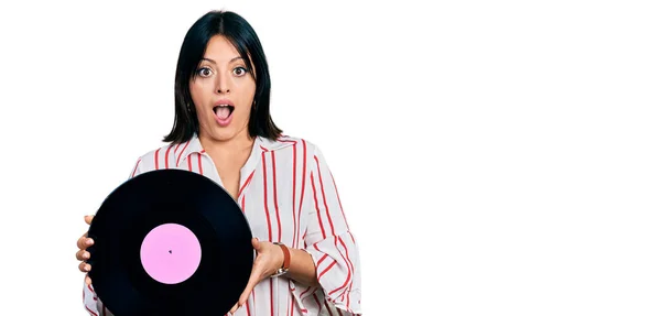 Young Hispanic Girl Holding Vinyl Disc Afraid Shocked Surprise Amazed — Stockfoto