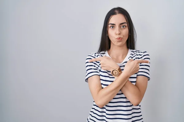 Young Brunette Woman Wearing Striped Shirt Pointing Both Sides Fingers — стоковое фото