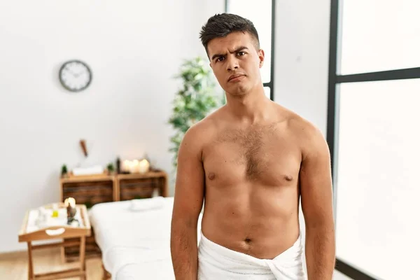 Young Hispanic Man Standing Shirtless Spa Center Skeptic Nervous Frowning — Stockfoto