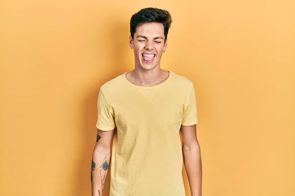 Joven Hombre Hispano Con Camiseta Amarilla Casual Sacando Lengua Feliz —  Fotos de Stock
