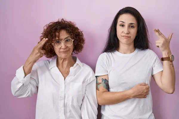 西班牙裔母亲和女儿穿着宽松的白色T恤 穿着粉色背景的衣服 手指手画脚 手指手画脚 一副自杀的姿势 — 图库照片