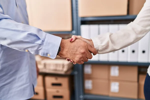 Middle age man and woman ecommerce business workers shake hands at office