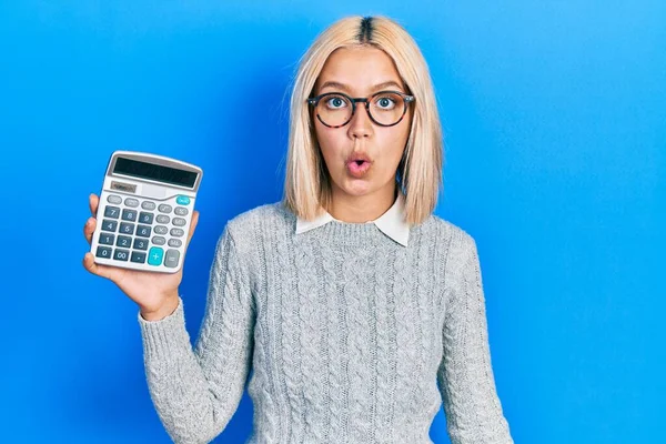 Beautiful Blonde Woman Showing Calculator Device Scared Amazed Open Mouth — Zdjęcie stockowe