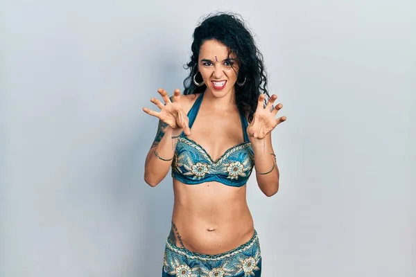 Young woman wearing bindi and traditional belly dance clothes smiling funny doing claw gesture as cat, aggressive and sexy expression