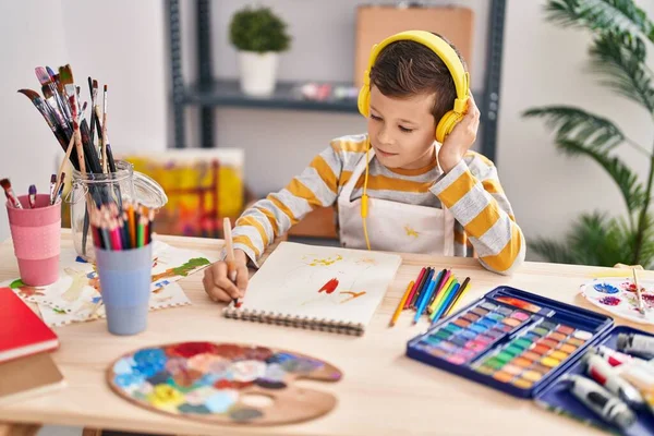 Blond child listening to music drawing at art studio