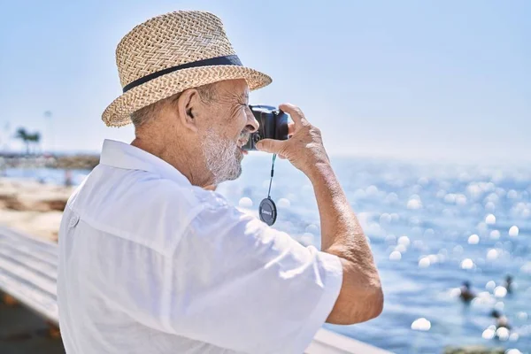 Senior Man Smiling Confident Wearing Summer Hat Using Camera Seaside — Stock Photo, Image