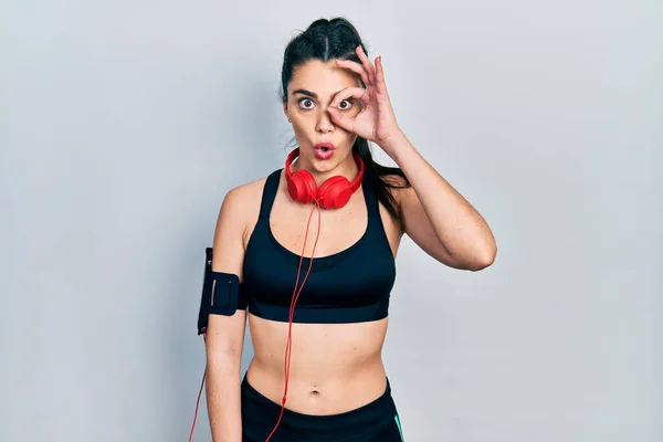 Young Hispanic Girl Wearing Gym Clothes Using Headphones Doing Gesture — Stock Fotó