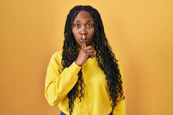 Африканская Женщина Стоящая Жёлтом Фоне Просит Тишины Пальцем Губах Молчание — стоковое фото