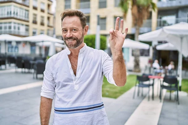 Şehirdeki orta yaşlı adam gülümsüyor. El ve parmaklarıyla 