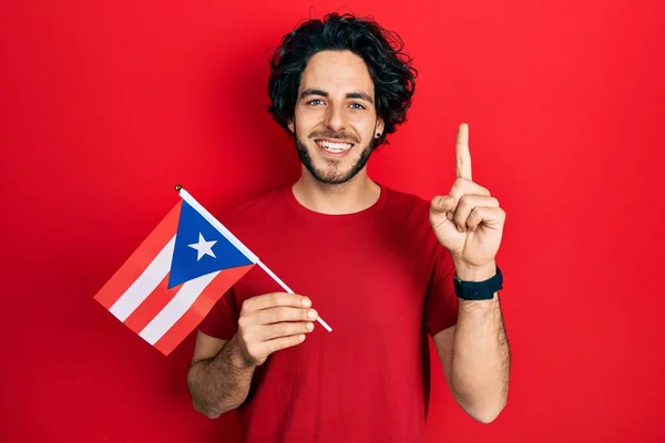 幸せな顔でアイデアや質問を指差す指で笑顔のプエルトリコのフラグを保持ハンサムなヒスパニック系の男 ナンバーワン — ストック写真