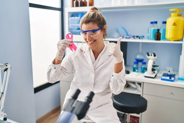 Νεαρή Γυναίκα Που Εργάζονται Εργαστήριο Επιστήμονας Κρατώντας Ροζ Κορδέλα Χαμογελώντας — Φωτογραφία Αρχείου