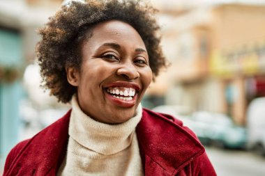 Güzel bir iş adamı Afro saçlı Amerikalı kadın şehirde mutlu ve kendinden emin bir şekilde gülümsüyor.