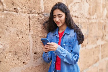 Sokakta akıllı telefon kullanan kendine güvenen genç İspanyol kız.