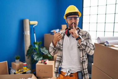 Sakallı, ev tadilatında çalışan genç, İspanyol bir adam parmakları yandan kenarı göstererek sessiz olmak istiyor. sessizlik ve gizli konsept. 