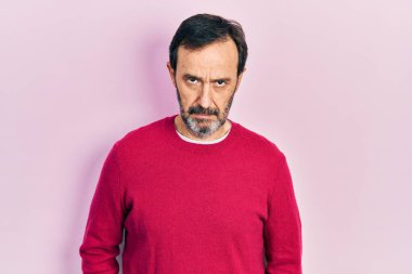 Orta yaşlı İspanyol bir adam gündelik kıyafetler giyiyor şüpheci ve gergin, sorun yüzünden surat asıyor. negatif kişi. 