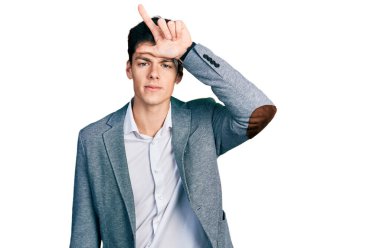 Genç İspanyol adam iş kıyafetleri giyiyor. Alnında parmakları olan insanlarla dalga geçiyor. Ezik jestler yapıyor.. 