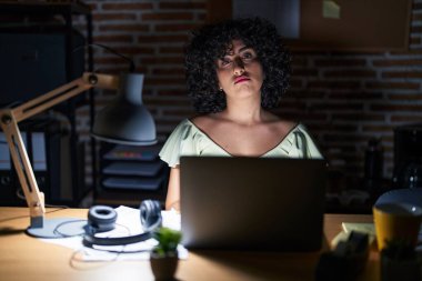 Geceleri ofiste çalışan kıvırcık saçlı genç esmer kadın uykulu ve yorgun görünüyor, yorgunluktan yorgun ve akşamdan kalma, sabahları tembel gözler.. 