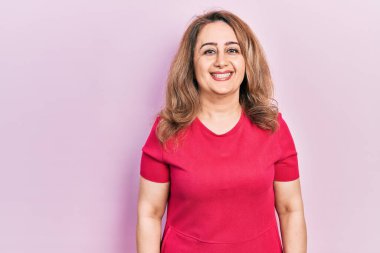 Orta yaşlı, beyaz, sıradan kıyafetler giyen mutlu ve havalı bir gülümsemesi olan bir kadın. şanslı kişi. 