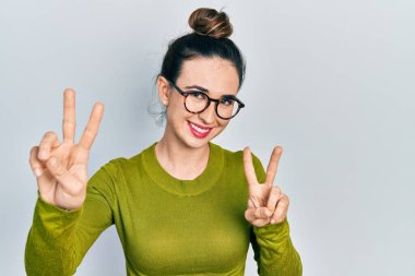 Gündelik kıyafetler ve gözlük takan genç İspanyol kız kameraya bakıp zafer işareti yapıyor. İki numara.. 