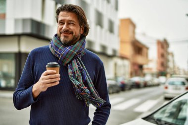 Orta yaşlı yakışıklı adam kasabada bir fincan kahve içiyor.