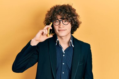 Yakışıklı genç adam akıllı telefondan konuşuyor. Olumlu ve mutlu görünüyor. Kendine güvenen bir gülümsemeyle dişlerini gösteriyor. 