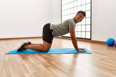 Genç İspanyol adam gülümsüyor spor merkezinde esniyor.