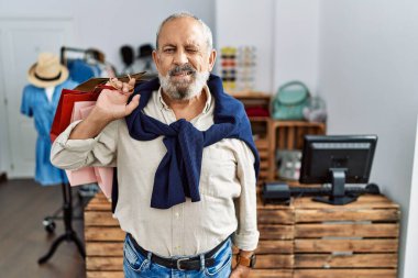 Yakışıklı son sınıf öğrencisi butik dükkanında alışveriş torbaları tutuyor kameraya seksi bir ifadeyle bakıyor, neşeli ve mutlu bir yüzle.. 