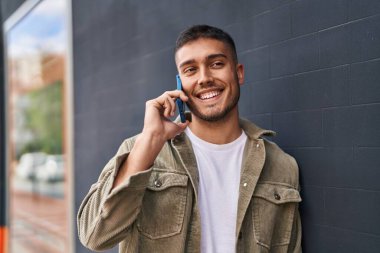 Genç İspanyol adam gülümsüyor. Kendine güveniyor. Sokakta akıllı telefondan konuşuyor.
