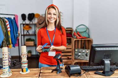 Giyim mağazasında çalışırken gülümseyen beyaz bir kadın..