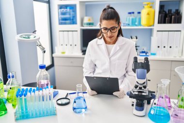 Laboratuvarda çalışan, bilim adamı üniforması giyen genç İspanyol kadın.