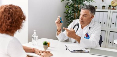 Doktor üniforması giyen orta yaşlı bir adam ve kadın klinikte tıbbi danışmanlık yapıyorlar.