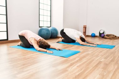 Olgun İspanyol çift yoga odasında egzersiz yapıyor ve esneme hareketleri yapıyor. İki yetişkin insan pilates ve esneklik egzersizi yapıyor.