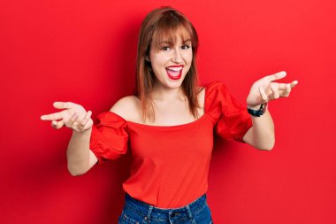 Kırmızı tişörtlü kızıl saçlı genç kadın gülümsüyor, yardım eli uzatıyor ve kabul ediyor.. 