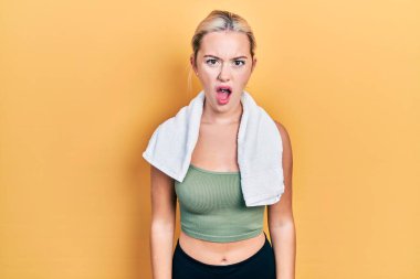 Spor kıyafetleri ve havlu giyen genç sarışın kız şaşkınlık ve şaşkınlık dolu bir ifade, korku ve heyecanlı bir yüz ifadesiyle dehşete düşmüş ve şok olmuştu.. 