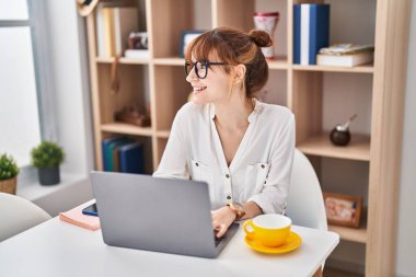 Young woman using laptop sitting on table at home