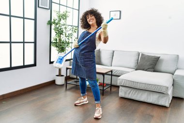 Ortadoğulu genç bir kadın evde temizlik yapıyor ve paspası gitar niyetine kullanıyor.