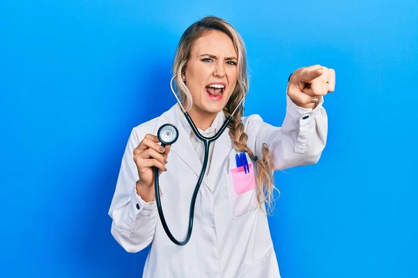 Piękna Młoda Blondynka Lekarz Kobieta Trzyma Stetoskop Wskazując Niezadowolony Sfrustrowany — Zdjęcie stockowe