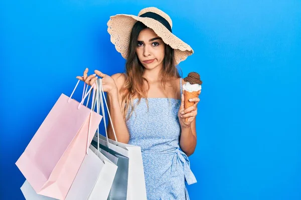 若いヒスパニック系の女の子のショッピングバッグやアイスクリーム懐疑的かつ神経を保持し 問題のために動揺を眉をひそめて 否定的な人 — ストック写真