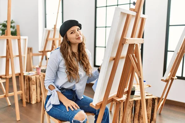 若いヒスパニックなアーティストの女性は絵を描く上でキャンバスアートスタジオ笑顔側を見て 離れて考えて見つめて — ストック写真