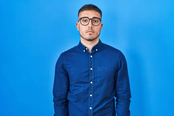 Mladý Hispánec Brýlích Modrém Pozadí Uvolnil Vážným Výrazem Tváři Jednoduchý — Stock fotografie