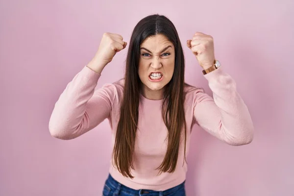 Giovane Donna Bruna Piedi Sfondo Rosa Arrabbiato Pazzo Alzando Pugni — Foto Stock