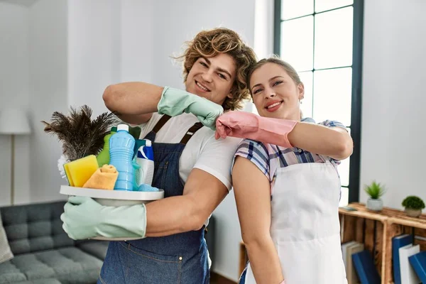 Jovem Casal Caucasiano Sorrindo Feliz Segurando Produtos Limpeza Bater Punhos — Fotografia de Stock