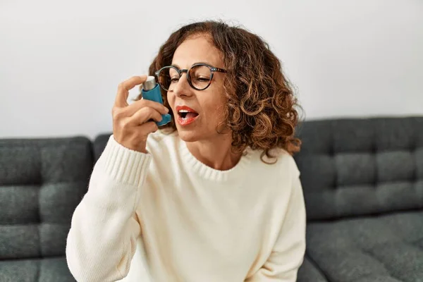 Dojrzała Latynoska Kobieta Stosująca Inhalator Astmy Siedząca Kanapie Domu — Zdjęcie stockowe
