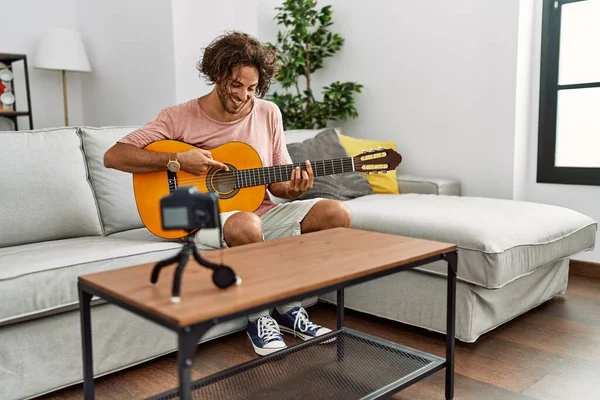 Evde klasik gitar çalan Latin asıllı genç bir adam kayıt yapıyor..