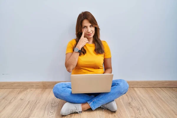 ヒスパニック系の女性を使用してノートパソコンを床の上に自宅であなたのジェスチャーを見て目を指して座って 疑わしい式 — ストック写真