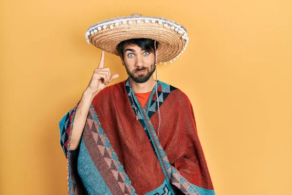 Jovem Hispânico Segurando Chapéu Mexicano Apontando Dedo Para Cima Com — Fotografia de Stock