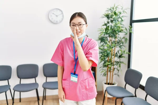 若いですアジアの看護師女性で医療待合室で手に口から秘密の噂を伝えます 悪意のある話の会話をささやく — ストック写真